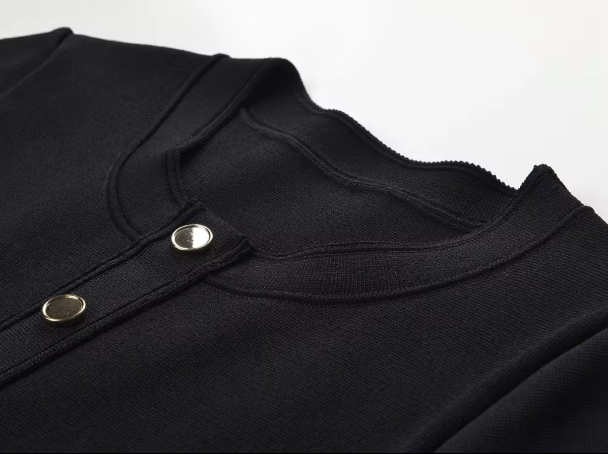 Black fitted dress with statement gold buttons and a playful pleated hem