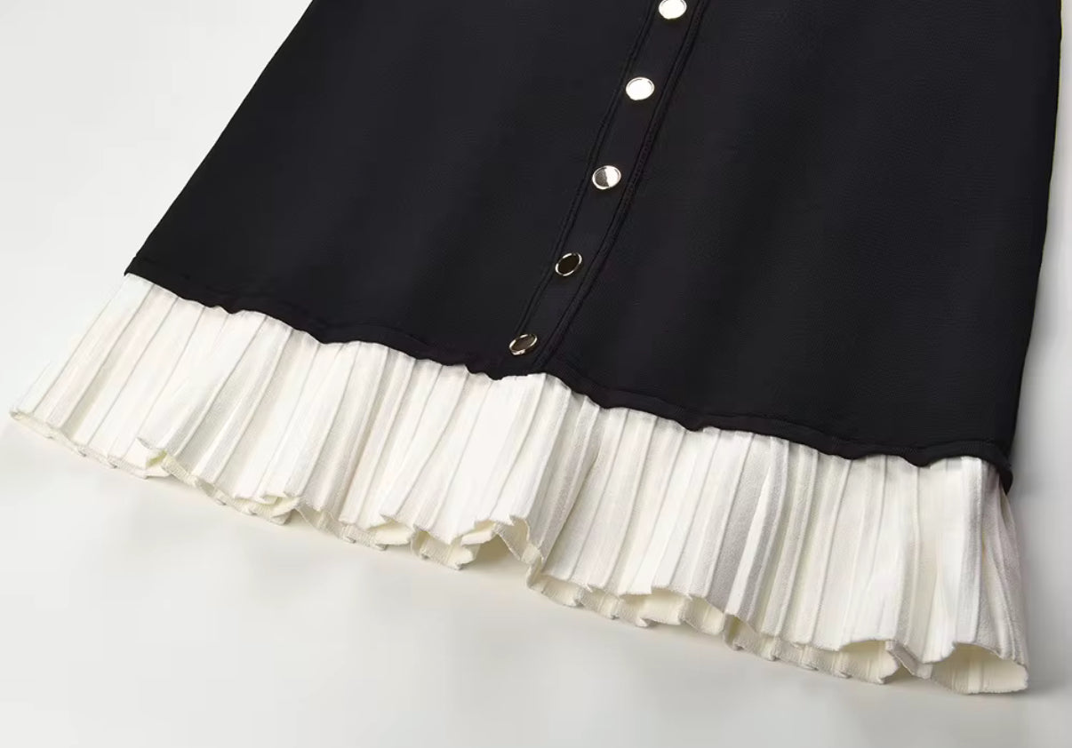 Black fitted dress with statement gold buttons and a playful pleated hem